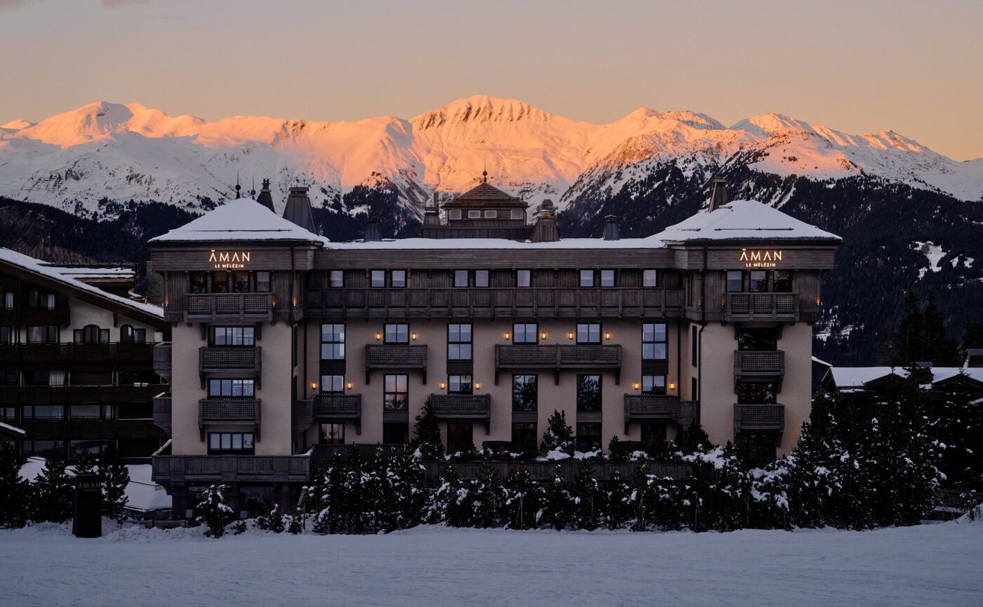 Aman Le M&eacute;l&eacute;zin lit at dusk beneath snow-covered Alpine slopes in Courchevel 1850