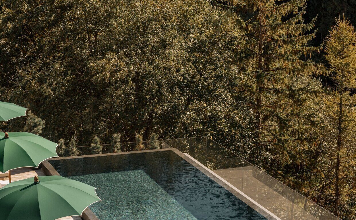 The outdoor pool at Aman Rosa Alpina overlooking the forested Italian Alps