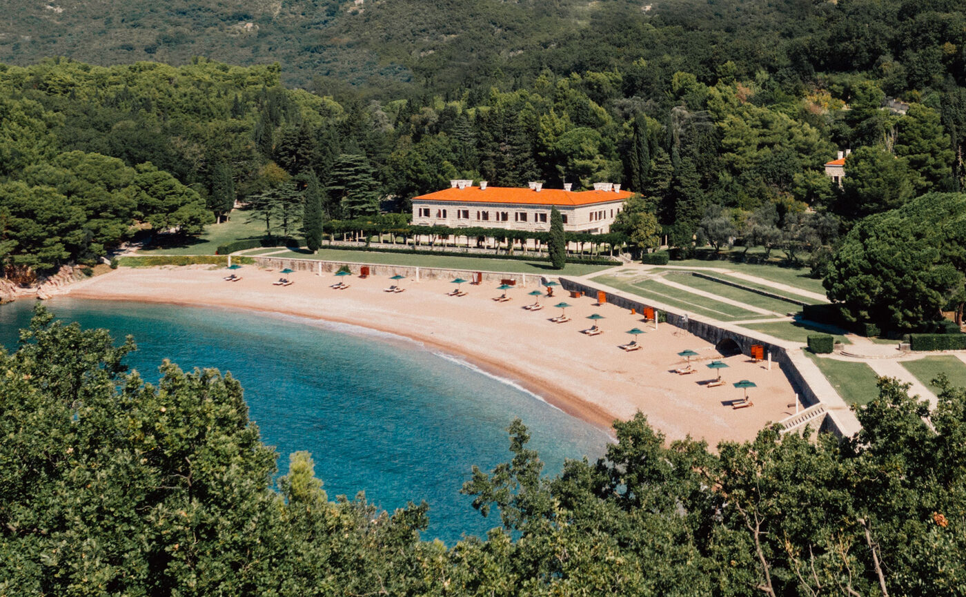 Aerial view of Sveti Stefan island village in Montenegro, linked to the mainland by a slim isthmus of sand.