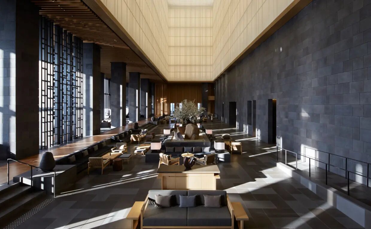 The washi-paper lantern ceiling and stone atrium of the Aman Tokyo lobby, lit by daylight