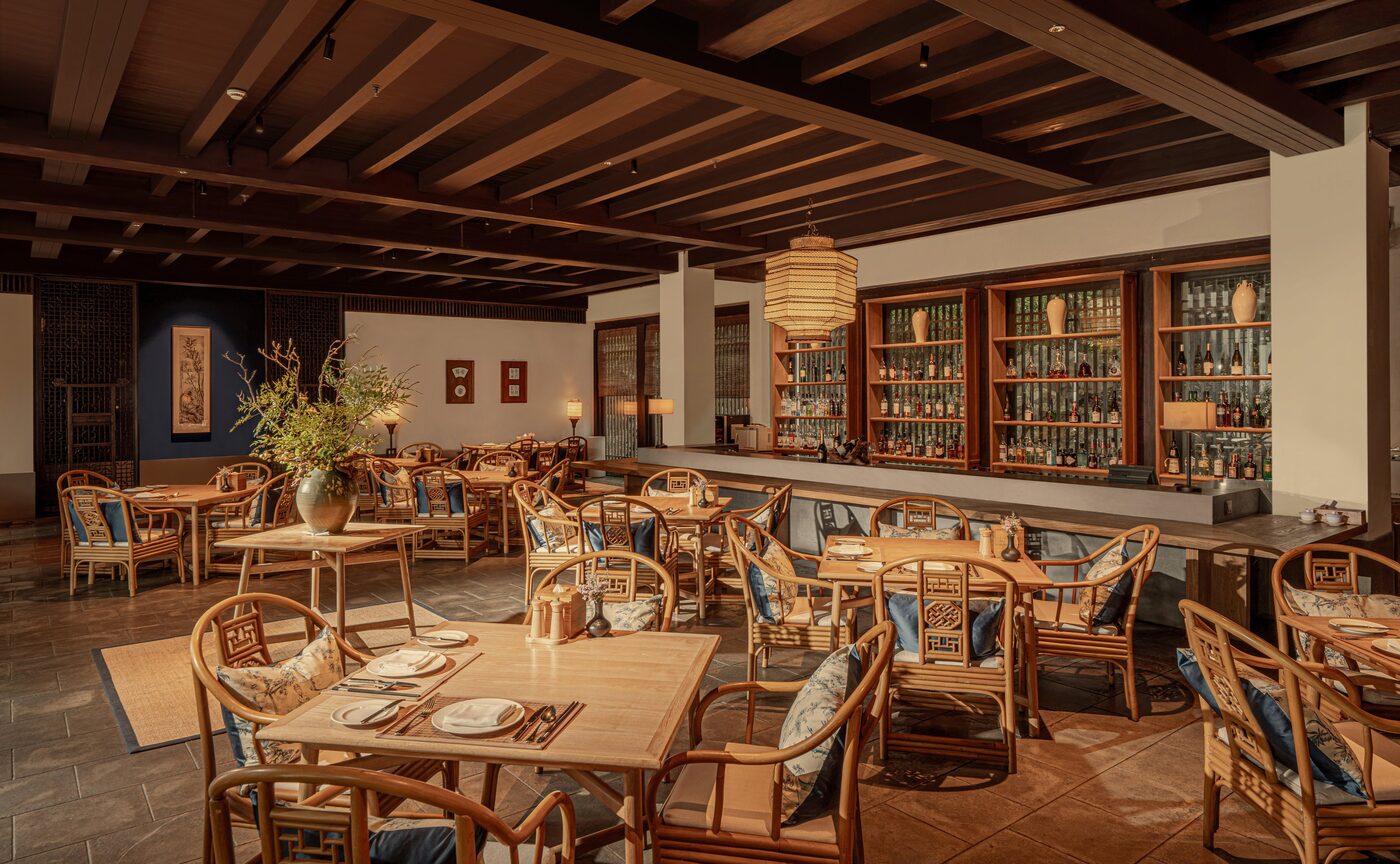 The dining room of Yuan at Amanfayun, Hangzhou, timber ceiling, rattan chairs and a back bar of spirits, courtesy of Aman