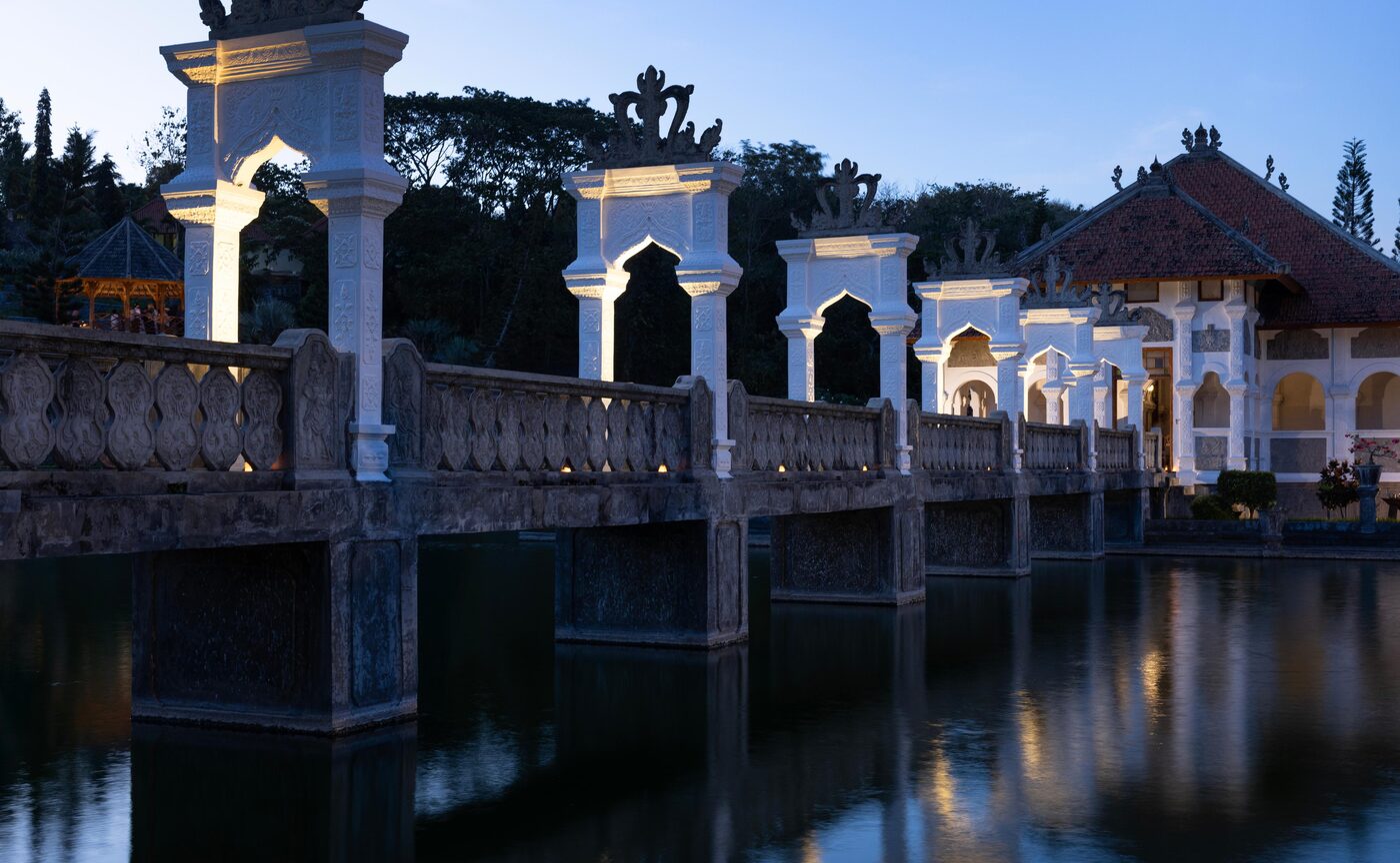 The pavilion of Ujung Water Palace reflected in its pool at dusk, set for Amankila's Karangasem Royal Dinner, courtesy of Aman