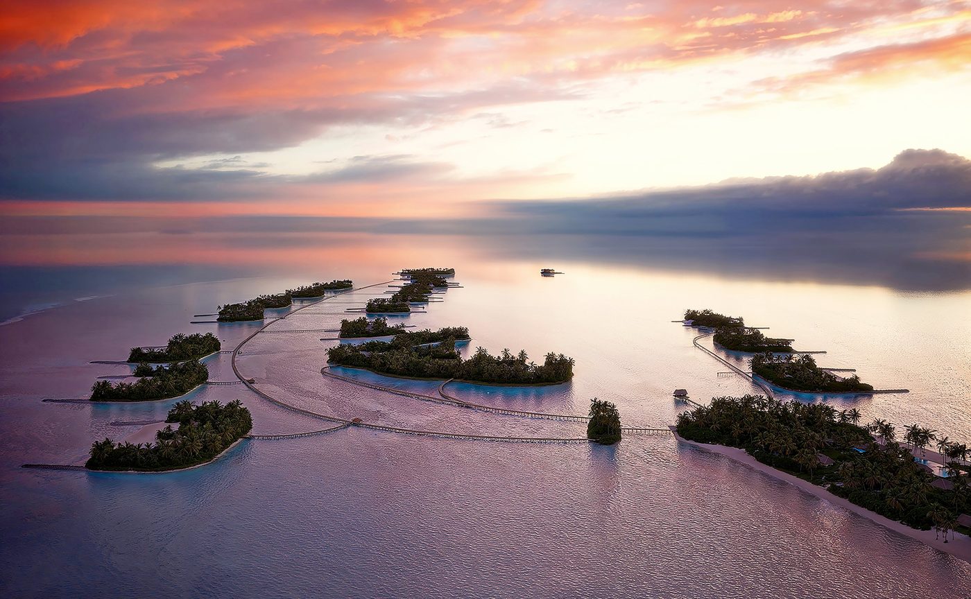 Aerial rendering of Amanolu at dusk, a line of small planted islands linked by low boardwalks across a pale lagoon in Vaavu Atoll, Maldives, courtesy of Aman