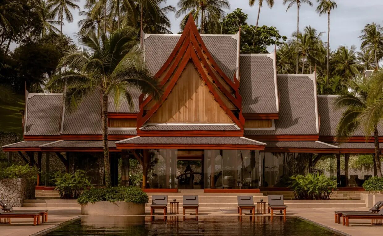 The main sala pavilion at Amanpuri with its pitched Thai roof, framed by coconut palms above the reflecting pool