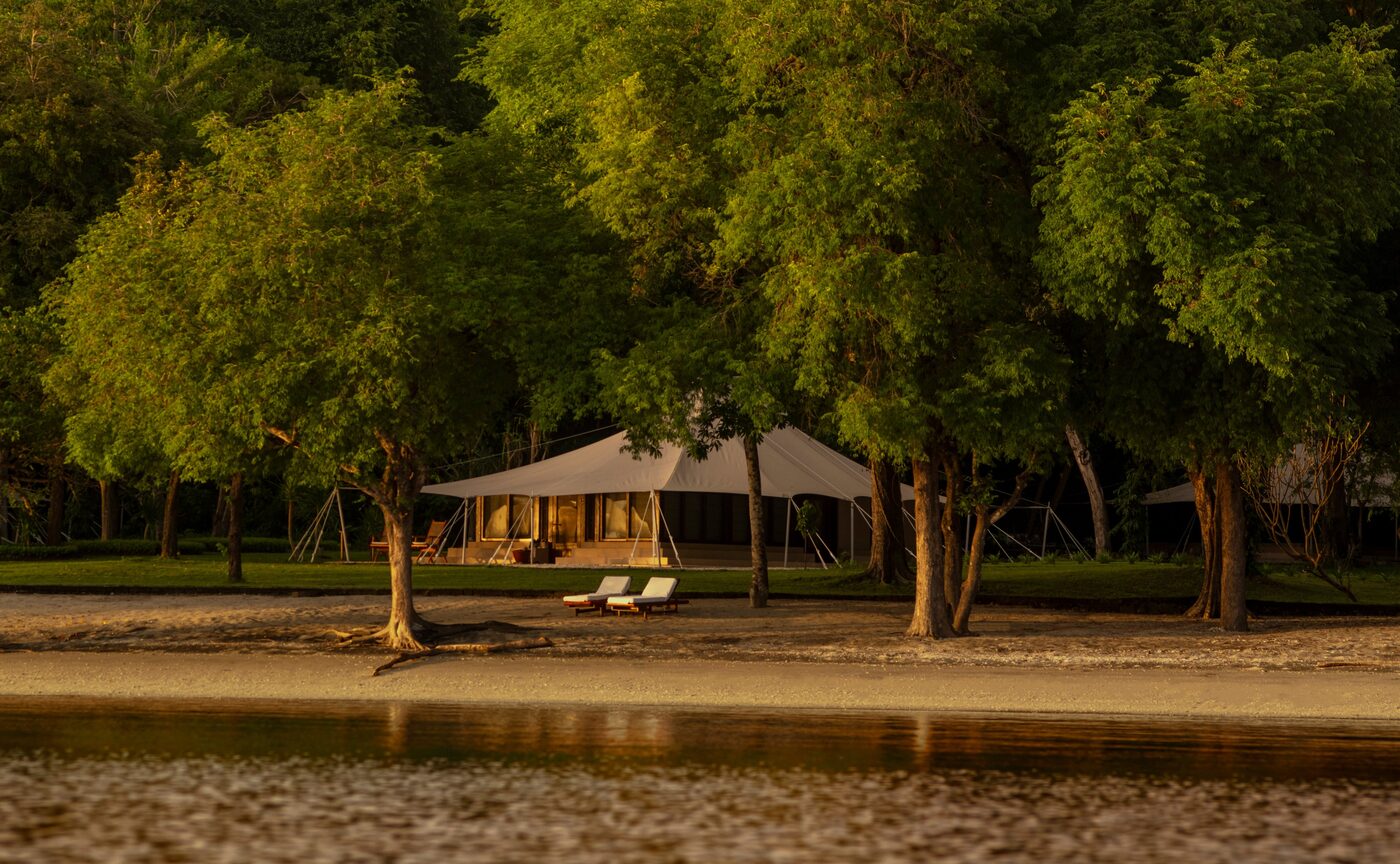 A canvas ocean tent at Amanwana framed by tall trees above the shore of Moyo Island