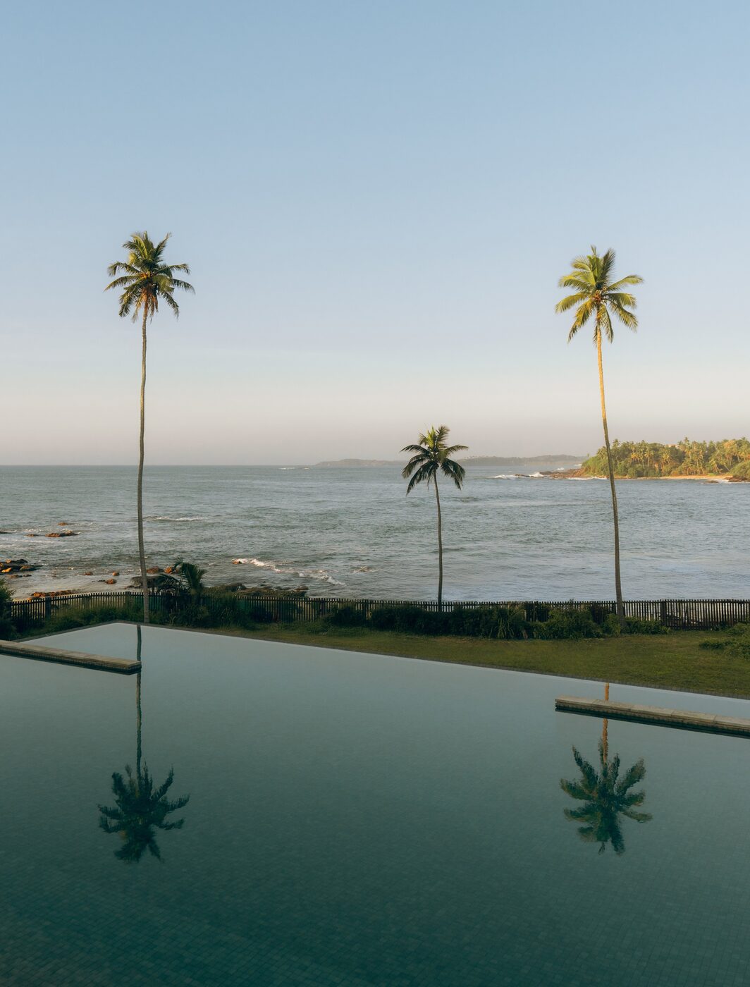 The infinity pool at Amanwella, Sri Lanka, reflecting palm trees with the Indian Ocean beyond
