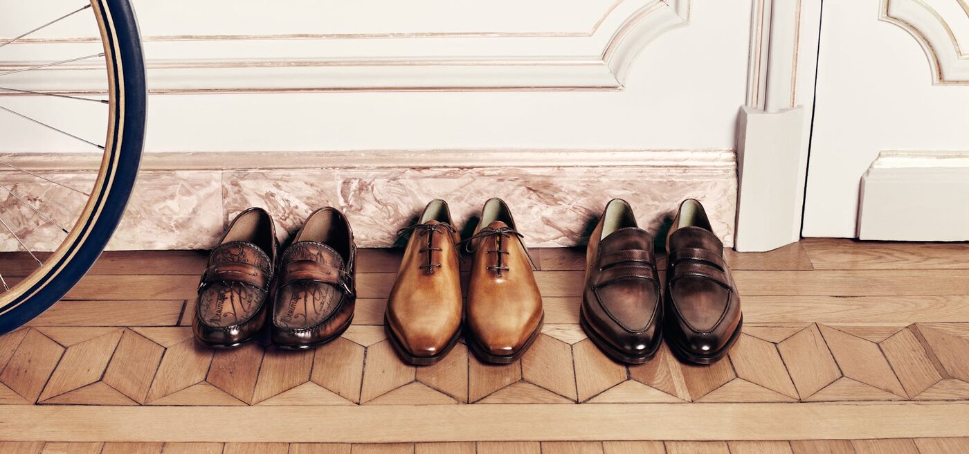 Three pairs of patinated Berluti shoes against a parquet floor in Paris