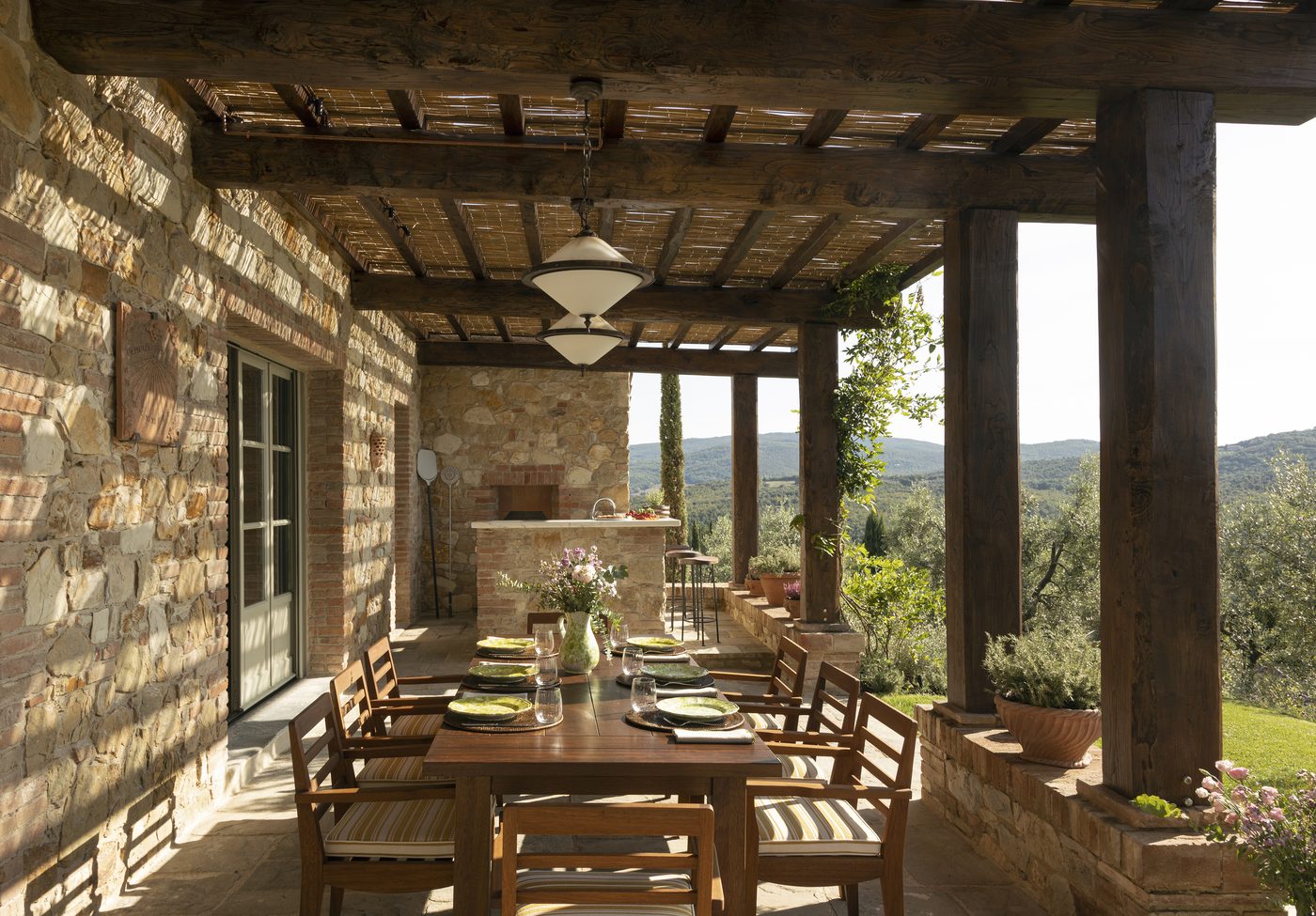 A covered stone terrace at Castello di Casole, A Belmond Hotel, Tuscany, looking over olive groves and hills