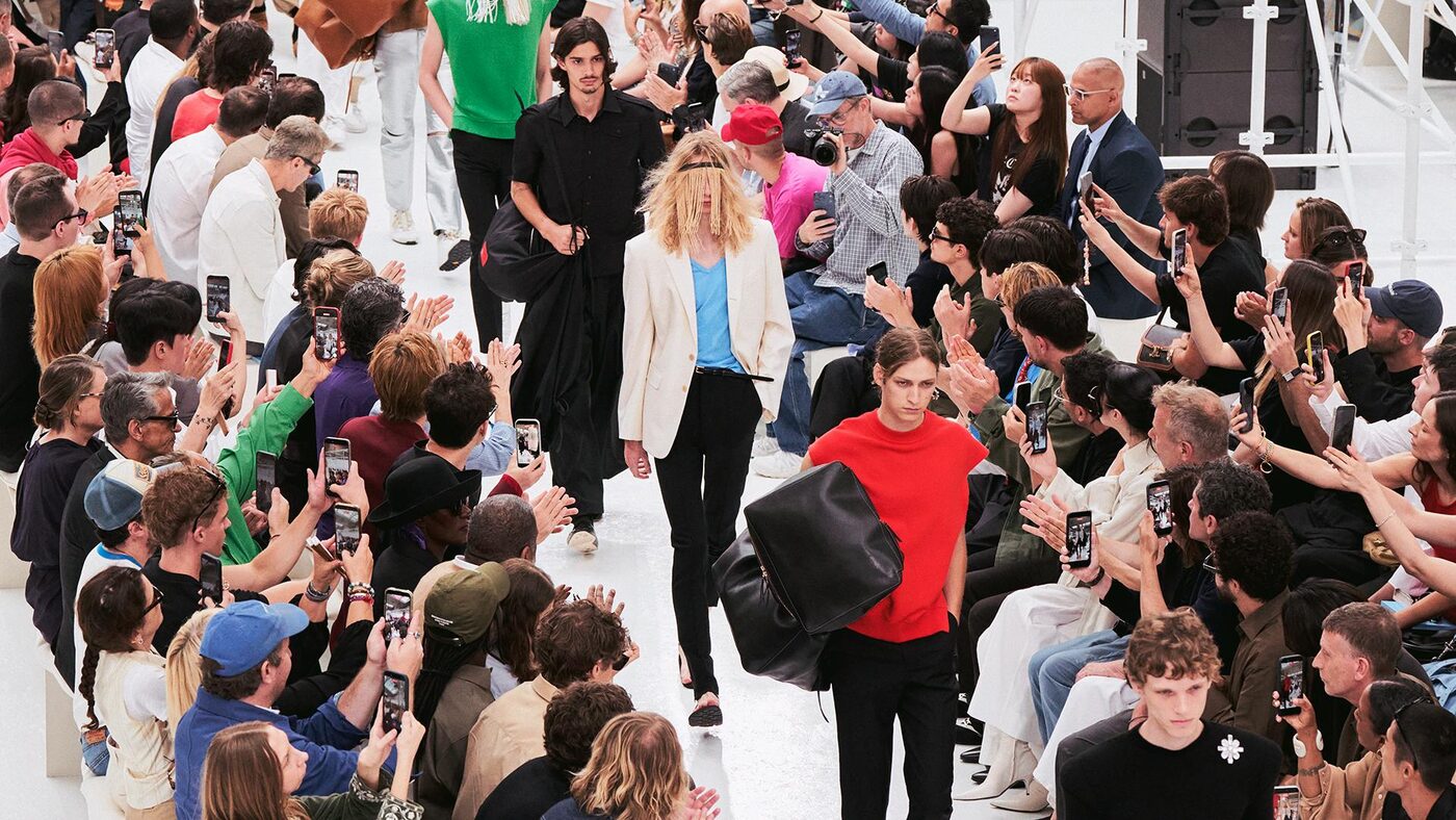 The finale of the Celine men's spring 2027 show, models walking a white runway between seated guests at the Tennis Club de Paris