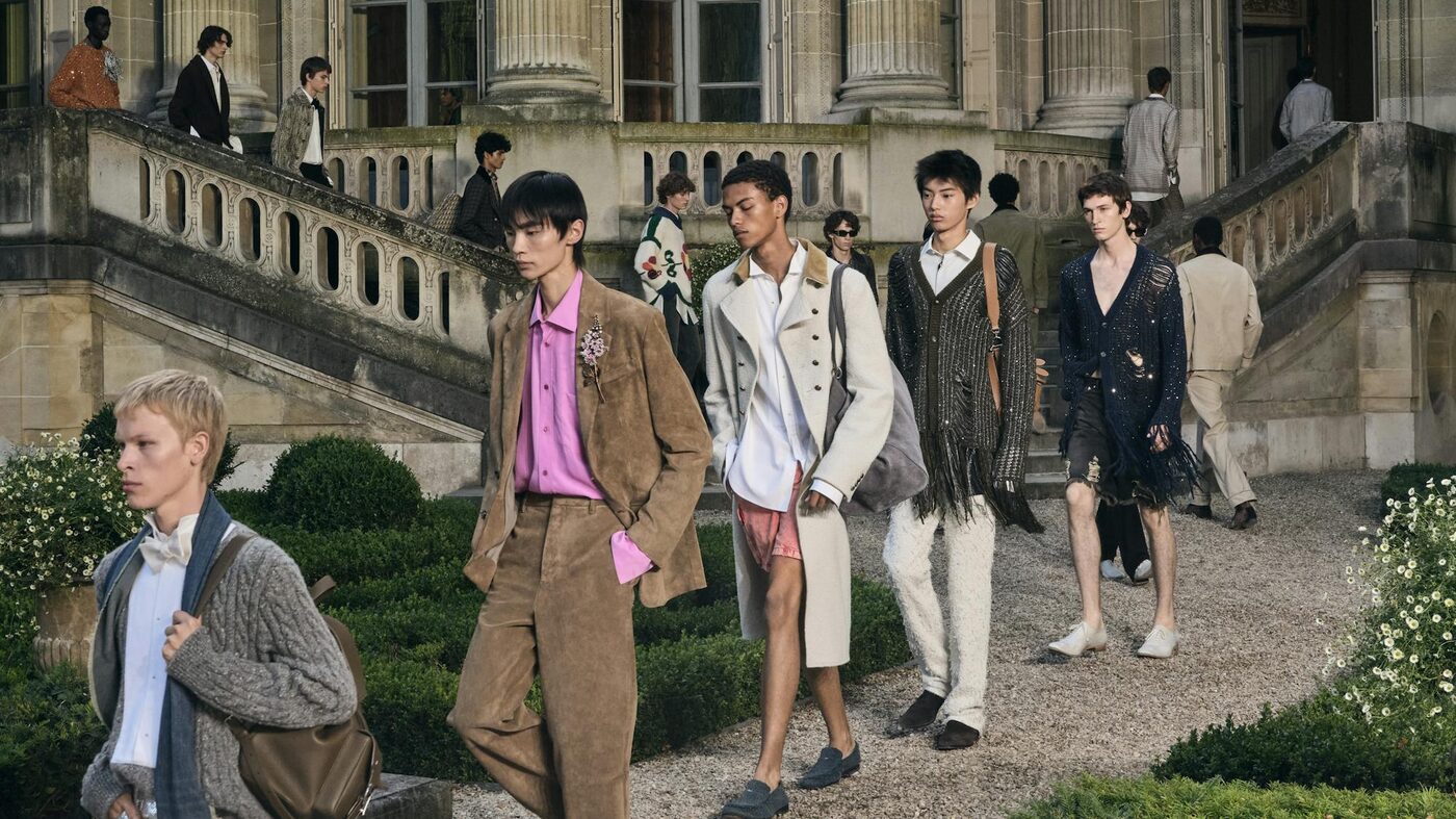 Models in the Dior Summer 2027 finale walking down the stone garden staircase of the Musée Nissim de Camondo in Paris, in suede tailoring, fringed cardigans and cream coats