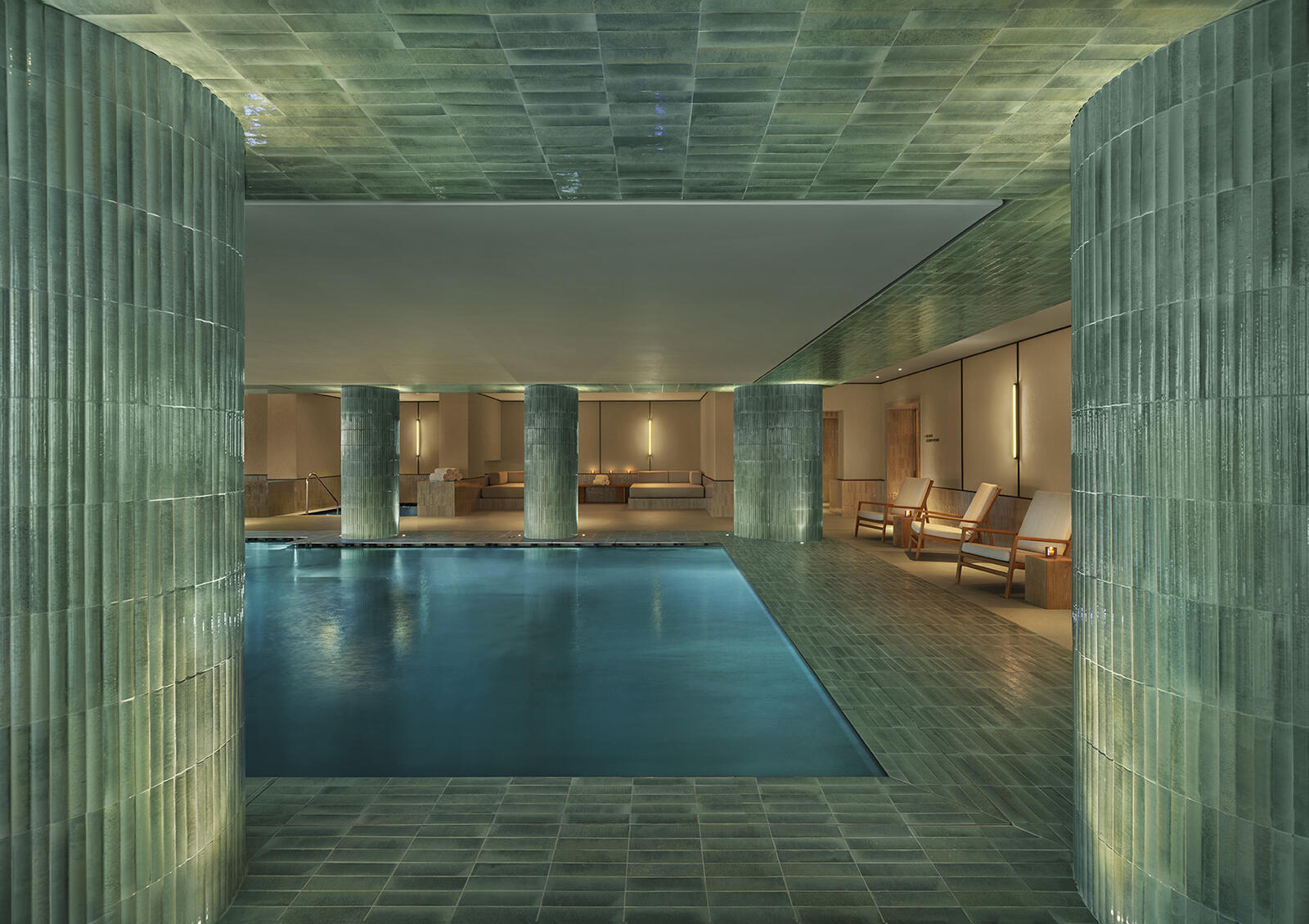 The Lake Como EDITION spa — green stone columns, indoor pool, warm ambient lighting