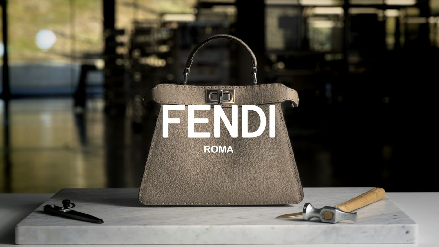 A taupe FENDI ROMA leather bag on a marble slab beside leather-working tools