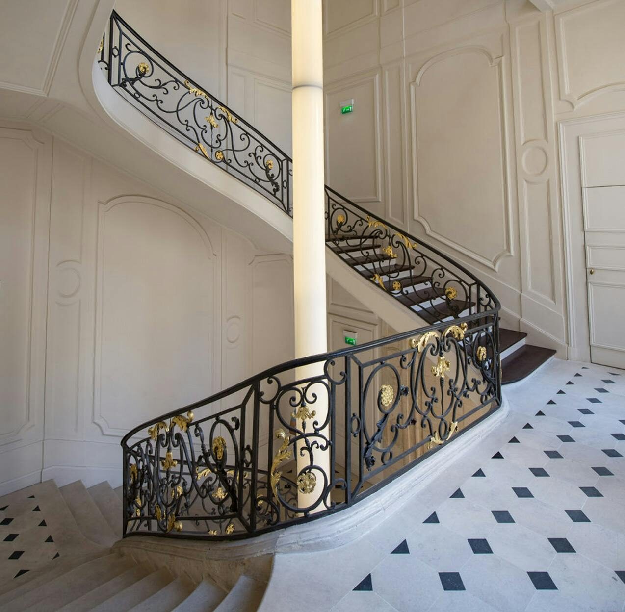 A sweeping Art Nouveau staircase inside Kenzo, with a gilt wrought-iron balustrade and chequerboard marble floor