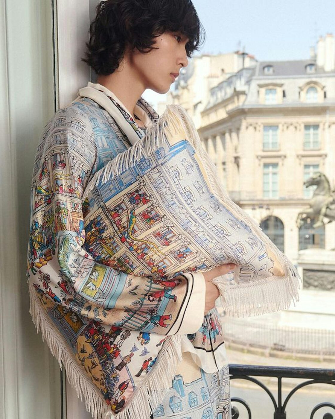 A Kenzo spring-summer 2027 look wrapped in an illustrated Place des Victoires print, the Paris square and the Louis XIV statue visible through the window