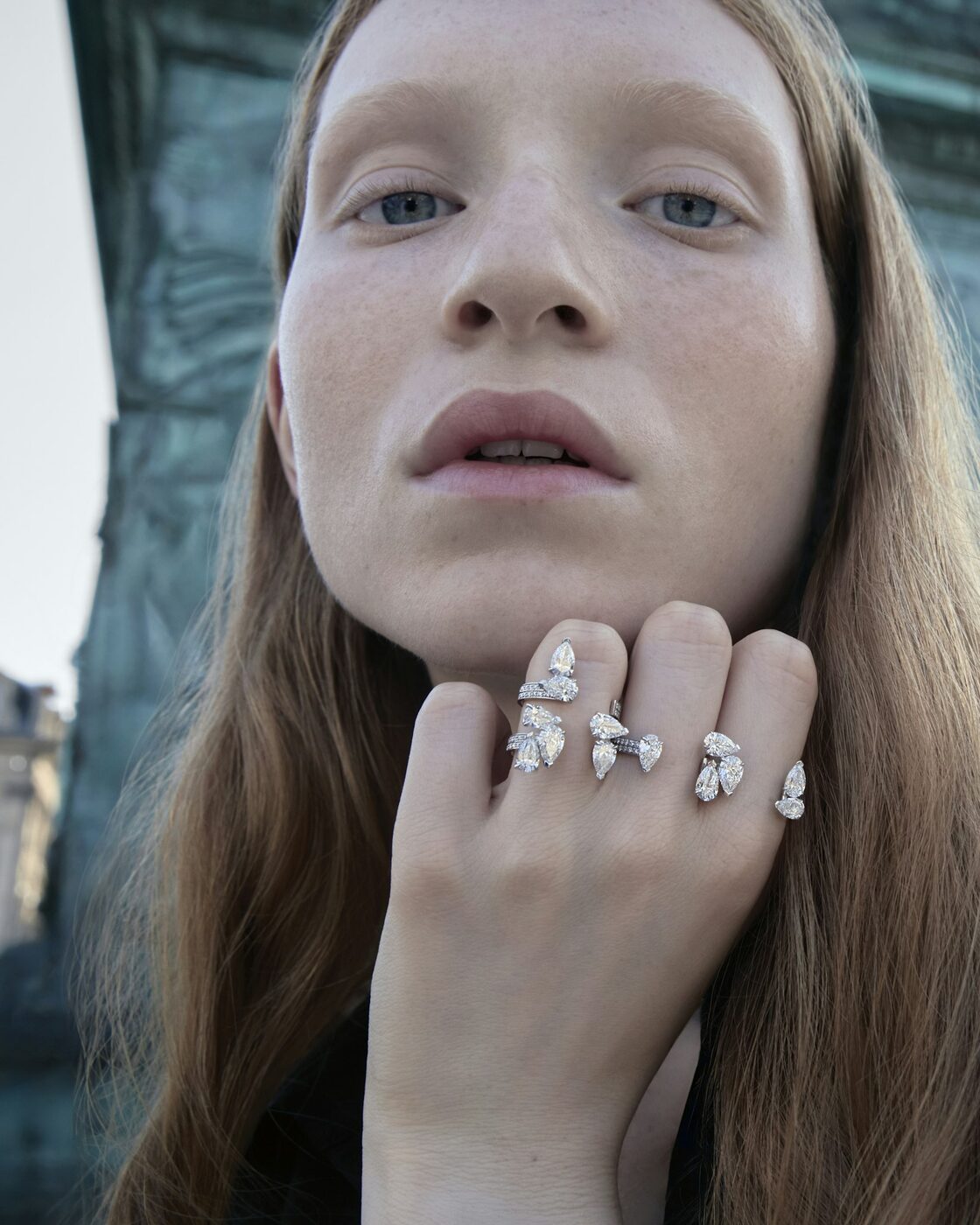 A model on Place Vend&ocirc;me wearing stacked Repossi diamond rings, the bronze relief of the Vend&ocirc;me column behind her